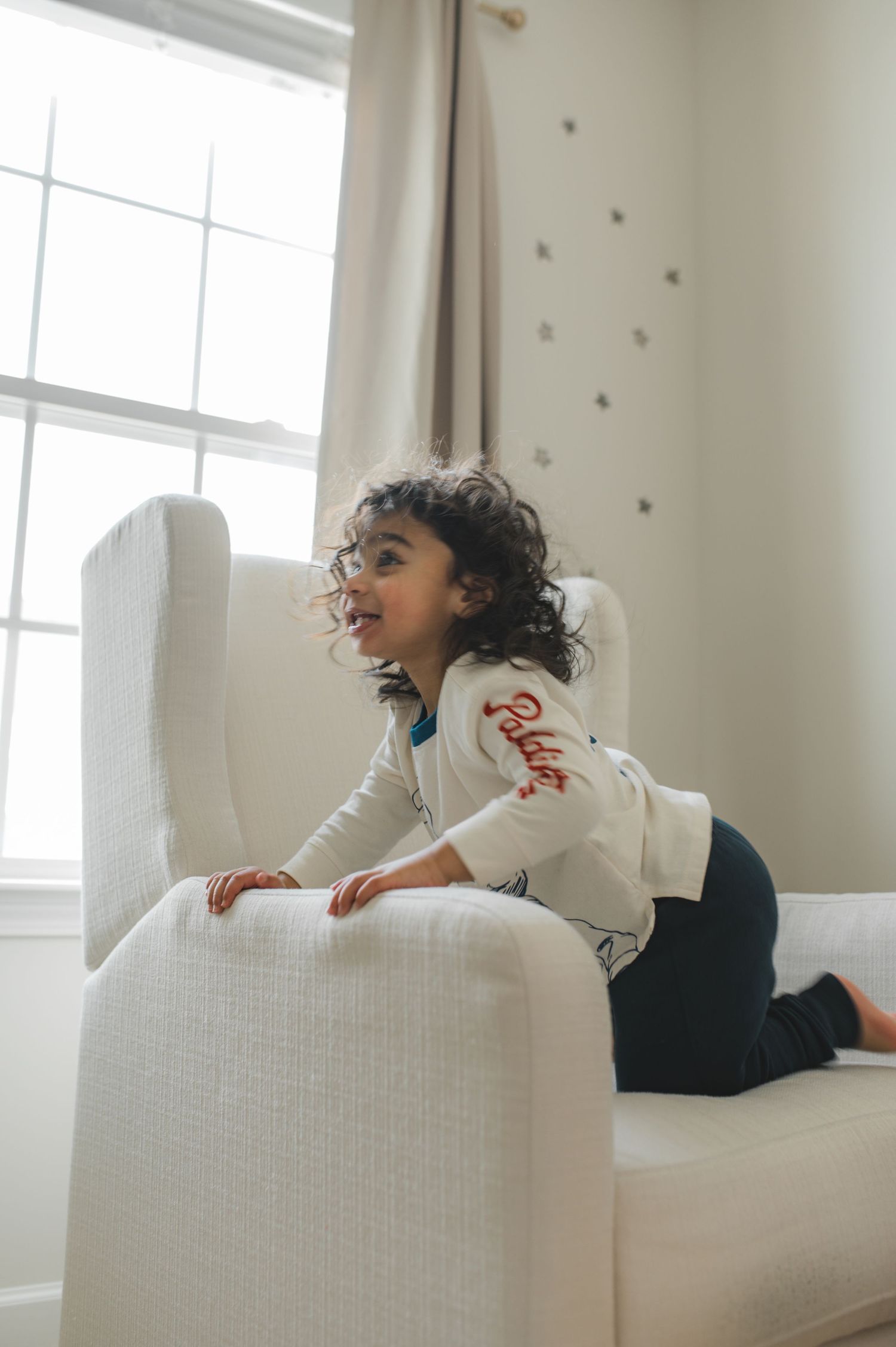 child playing near window, sitting in rocking chair