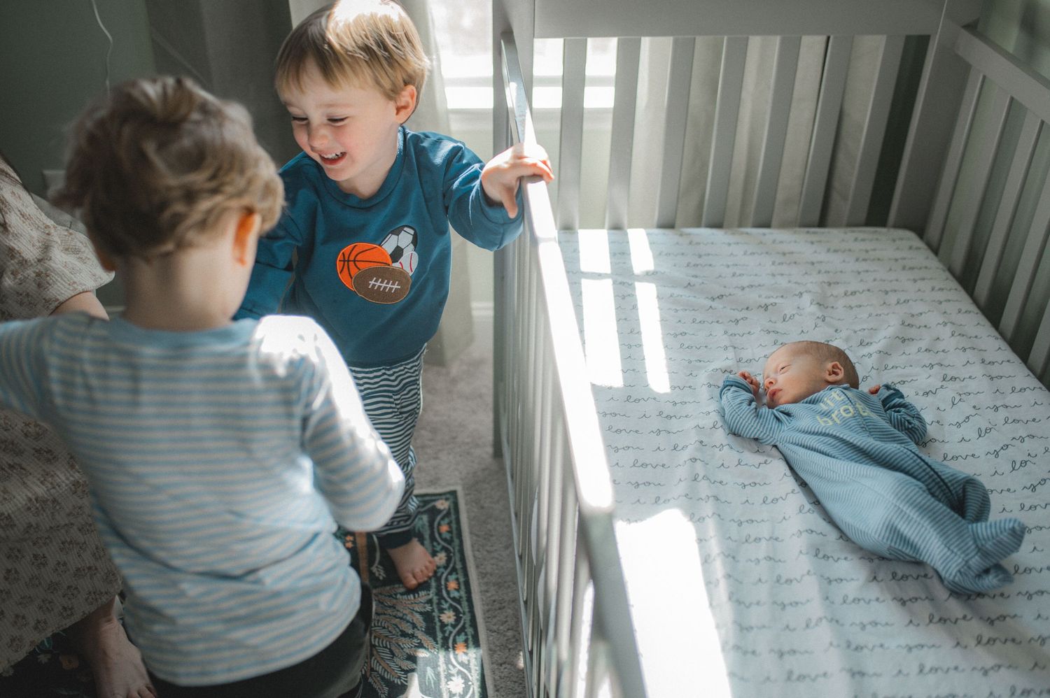 twin boys playing in nursery by crib and newborn twins