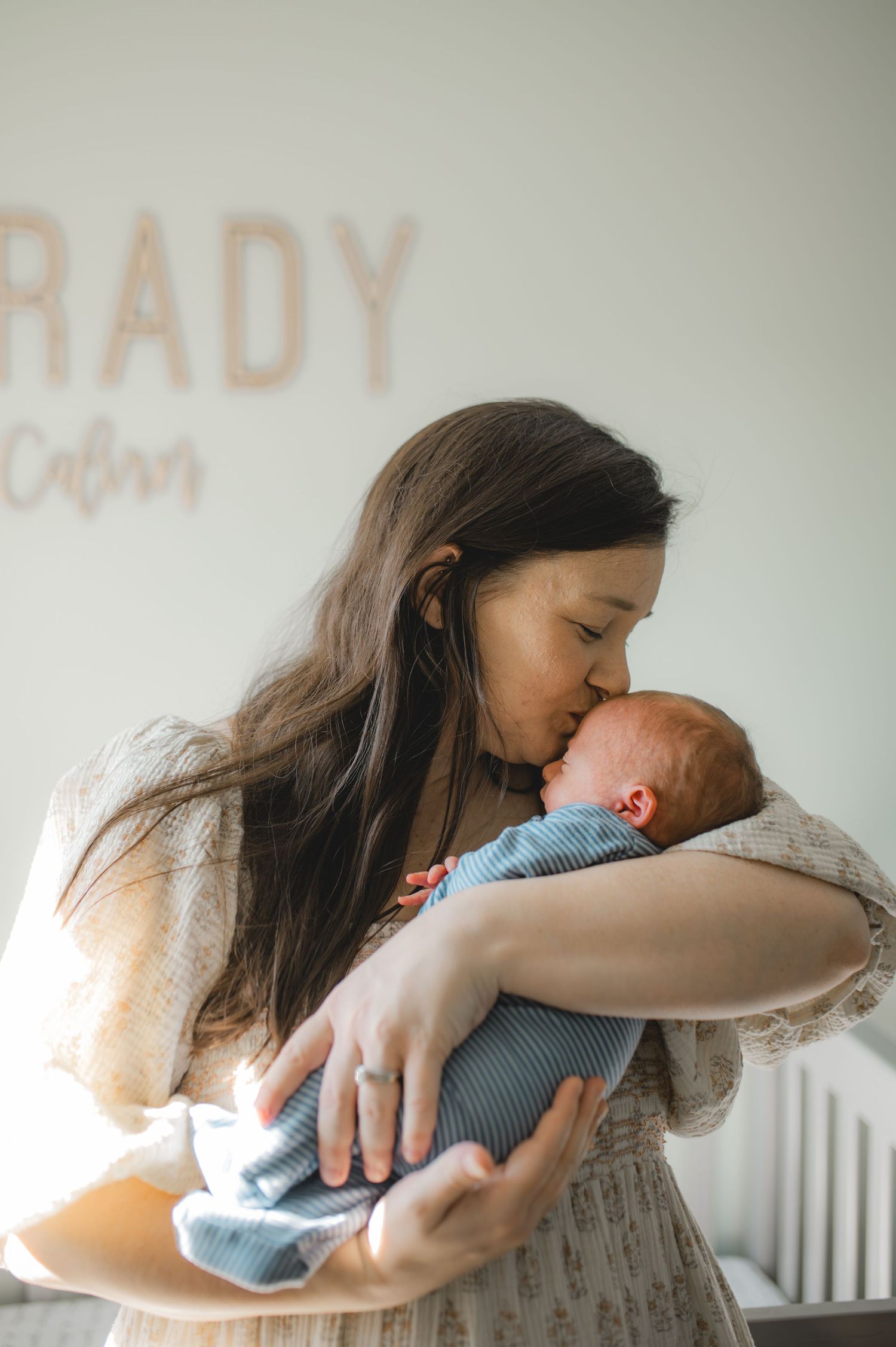 mom and baby standing in front of crib in nursery, greenville nc newborn photographer
