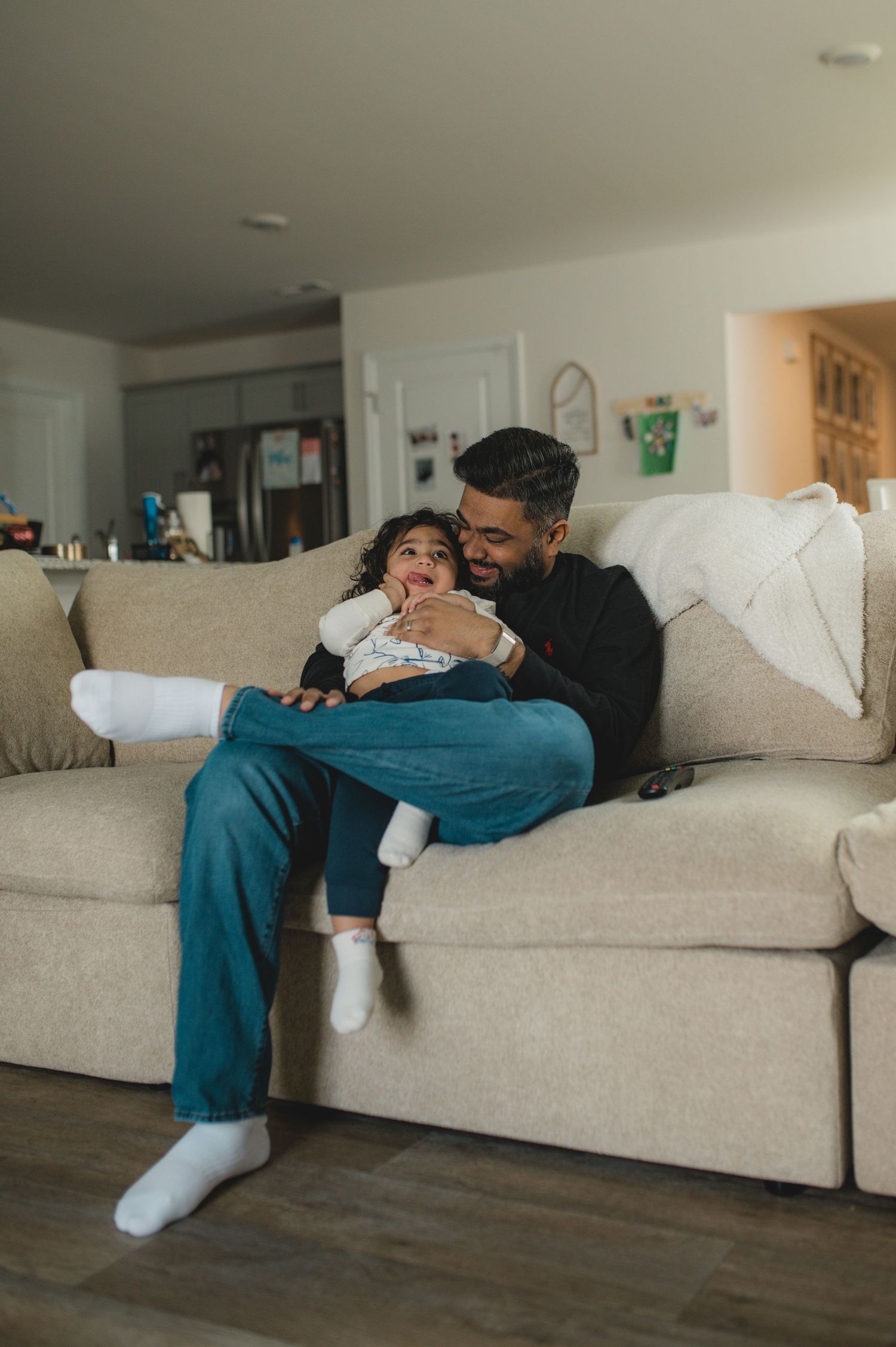 dad and son sitting on couch watching tv and snuggling, family at home documentary photography session