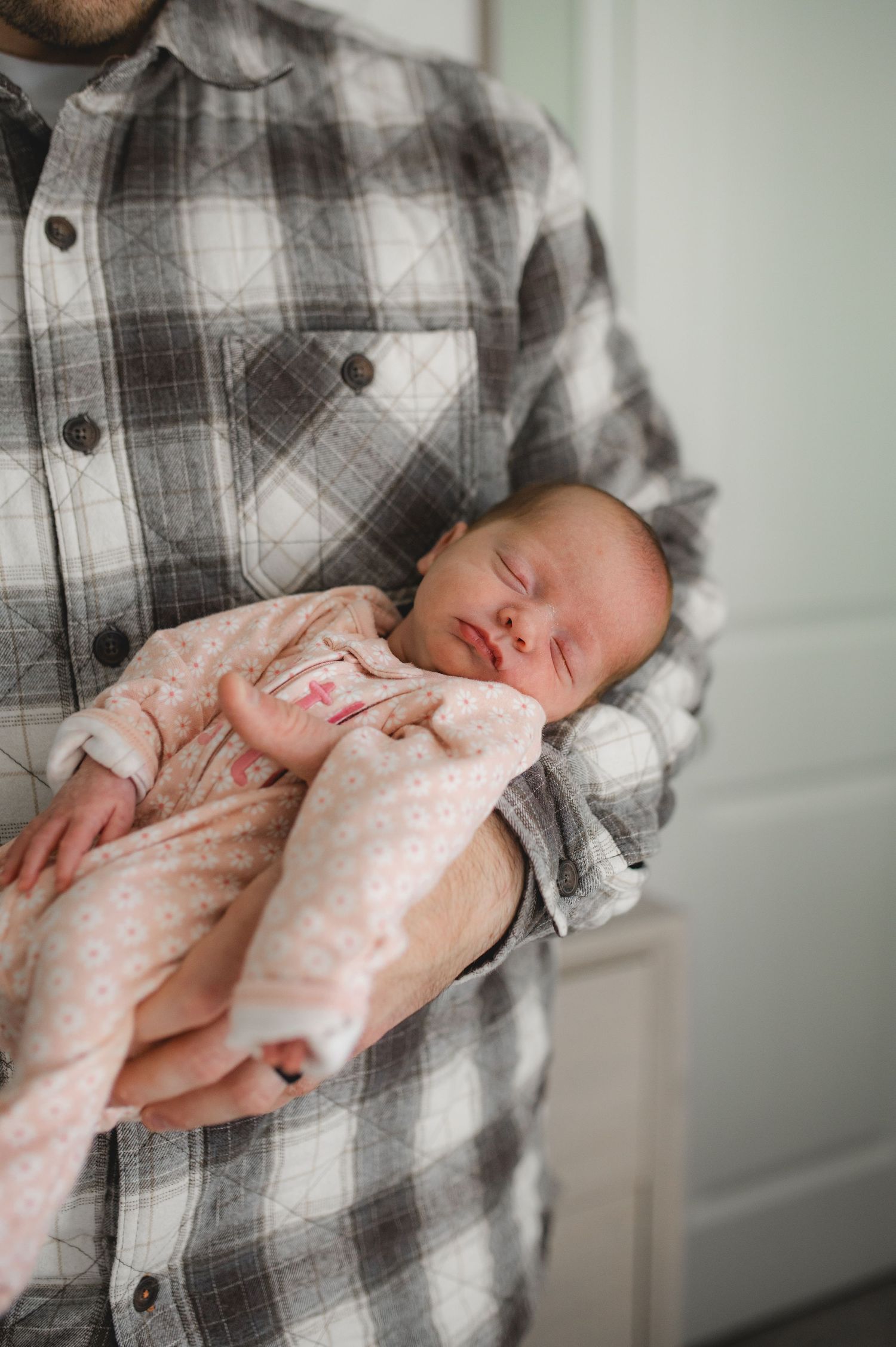 dad holding newborn baby girl asleep
