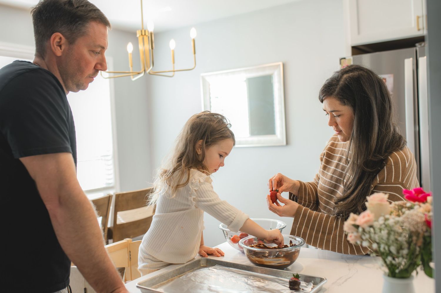 mom dad and child with baking tray and bowl of strawberries and chocolate, greenville, nc