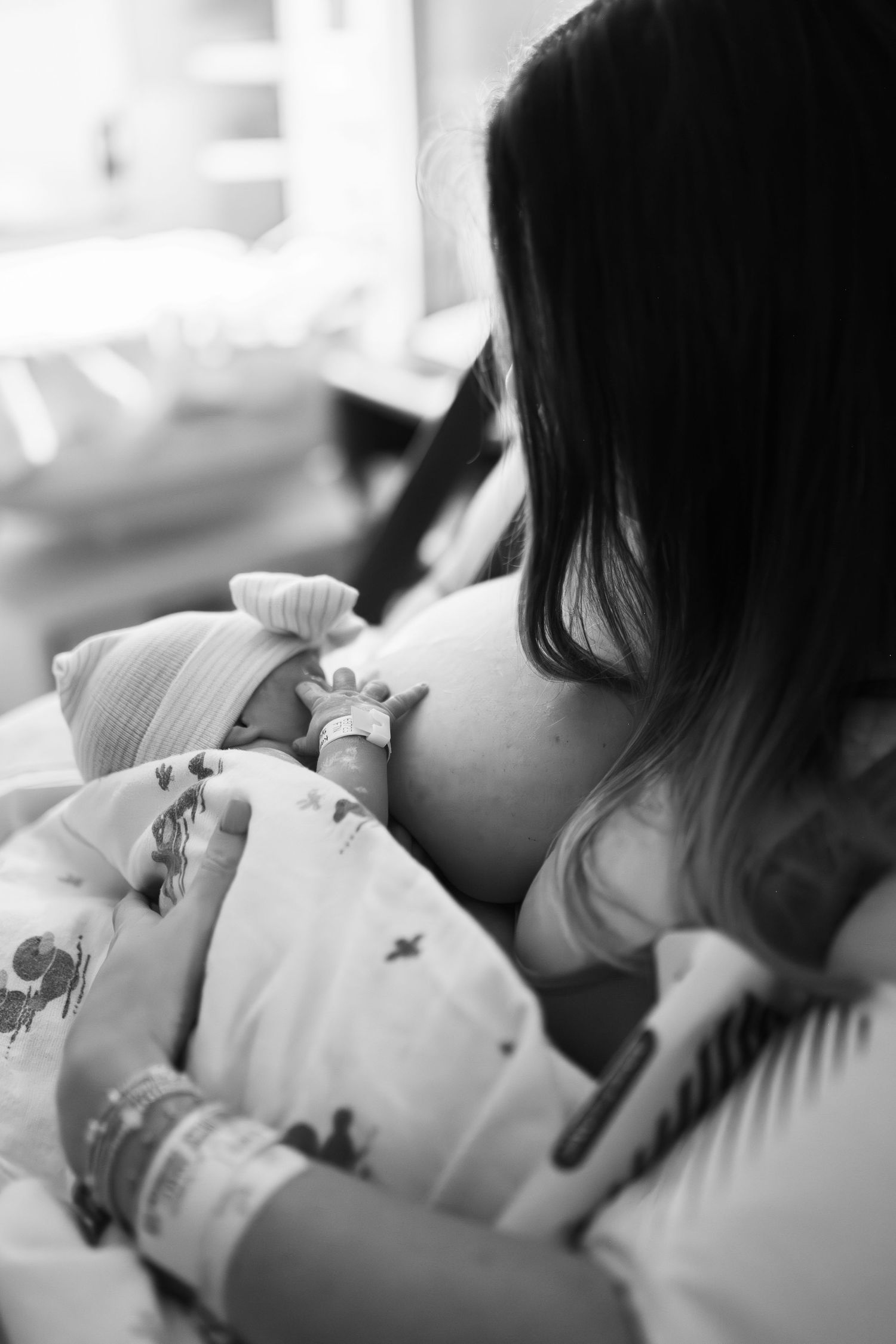 mom breastfeeding baby girl after birth in hospital at ECU Health Medical Center for the first time