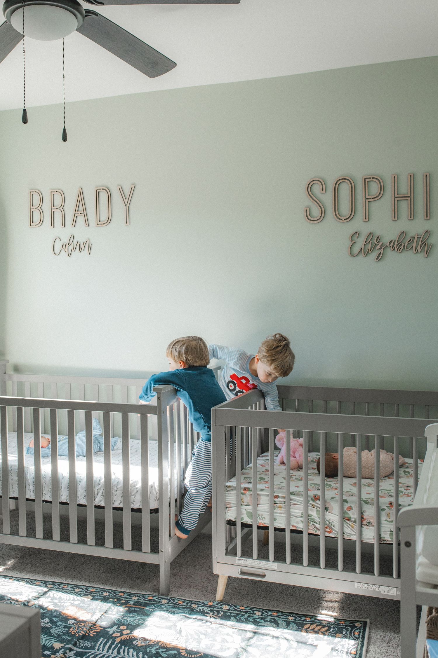 twin boys playing in nursery by crib and newborn twins