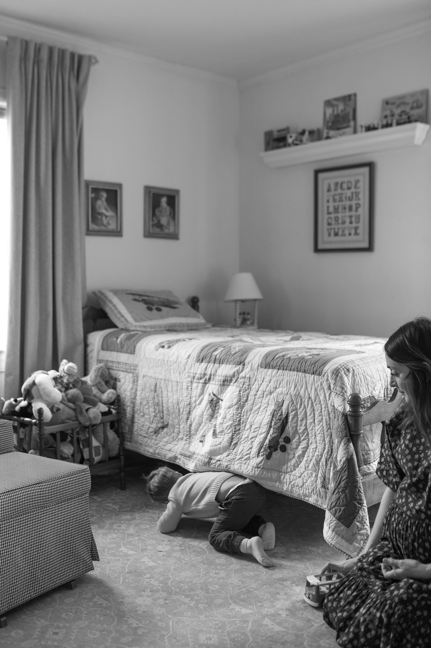 mom and child playing on floor in front of bed with wooden toys