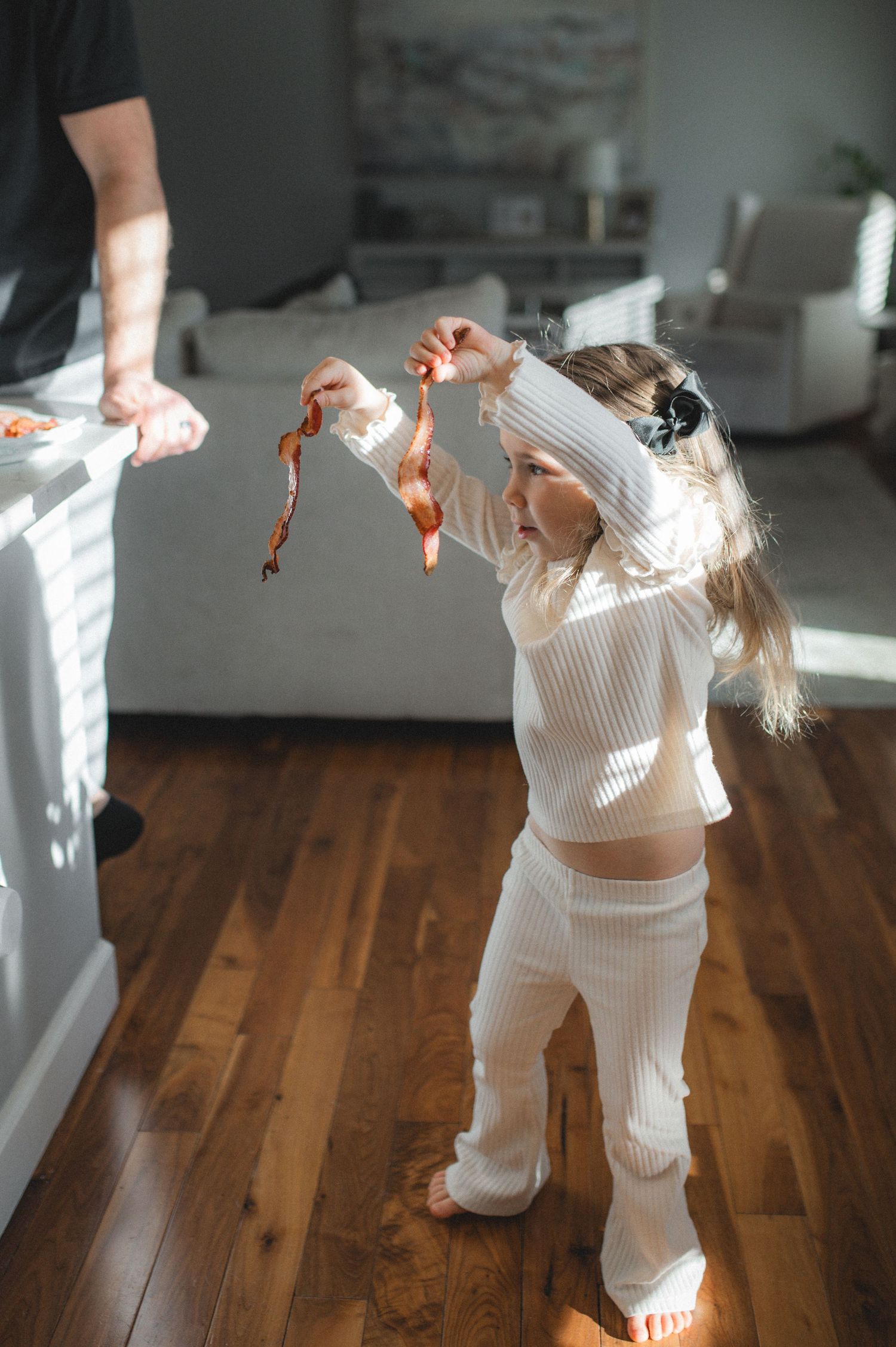 child holding strips of bacon dancing in kitchen