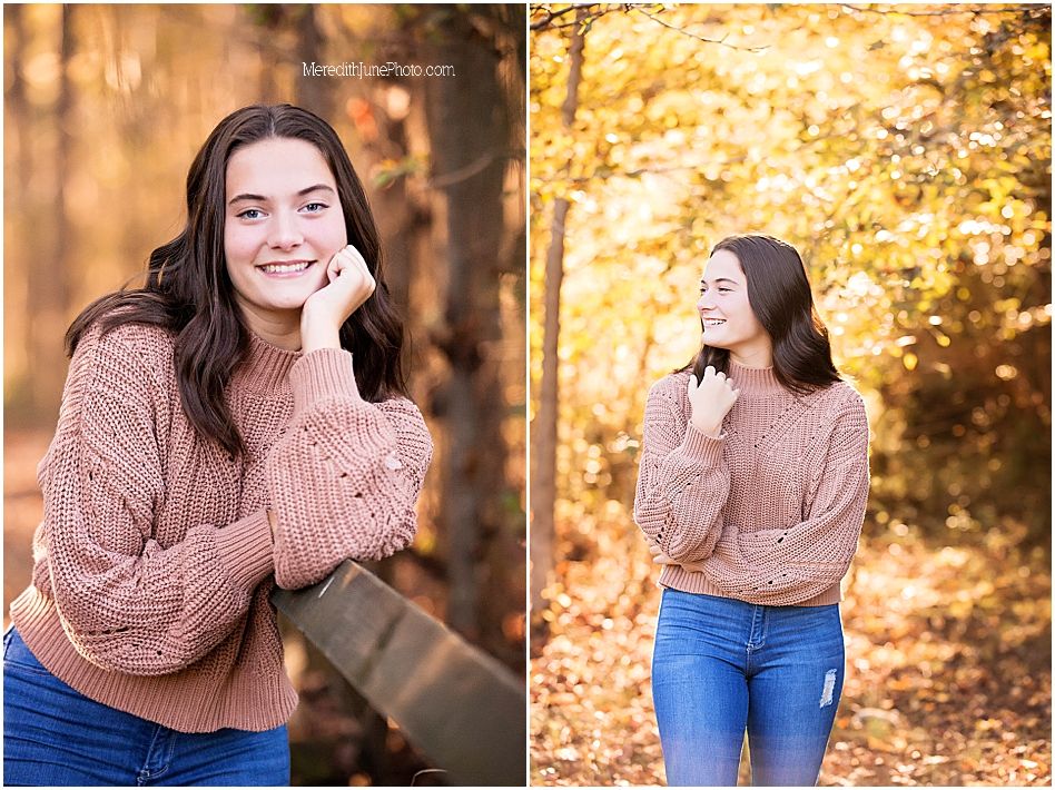 Young woman in cozy brown sweater poses outdoors during fall season with autumn colors in background.