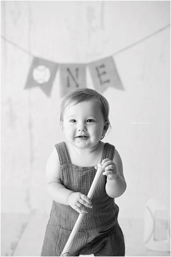 A series of high-key black and white portraits showing a baby in a gray dress smiling and playing.