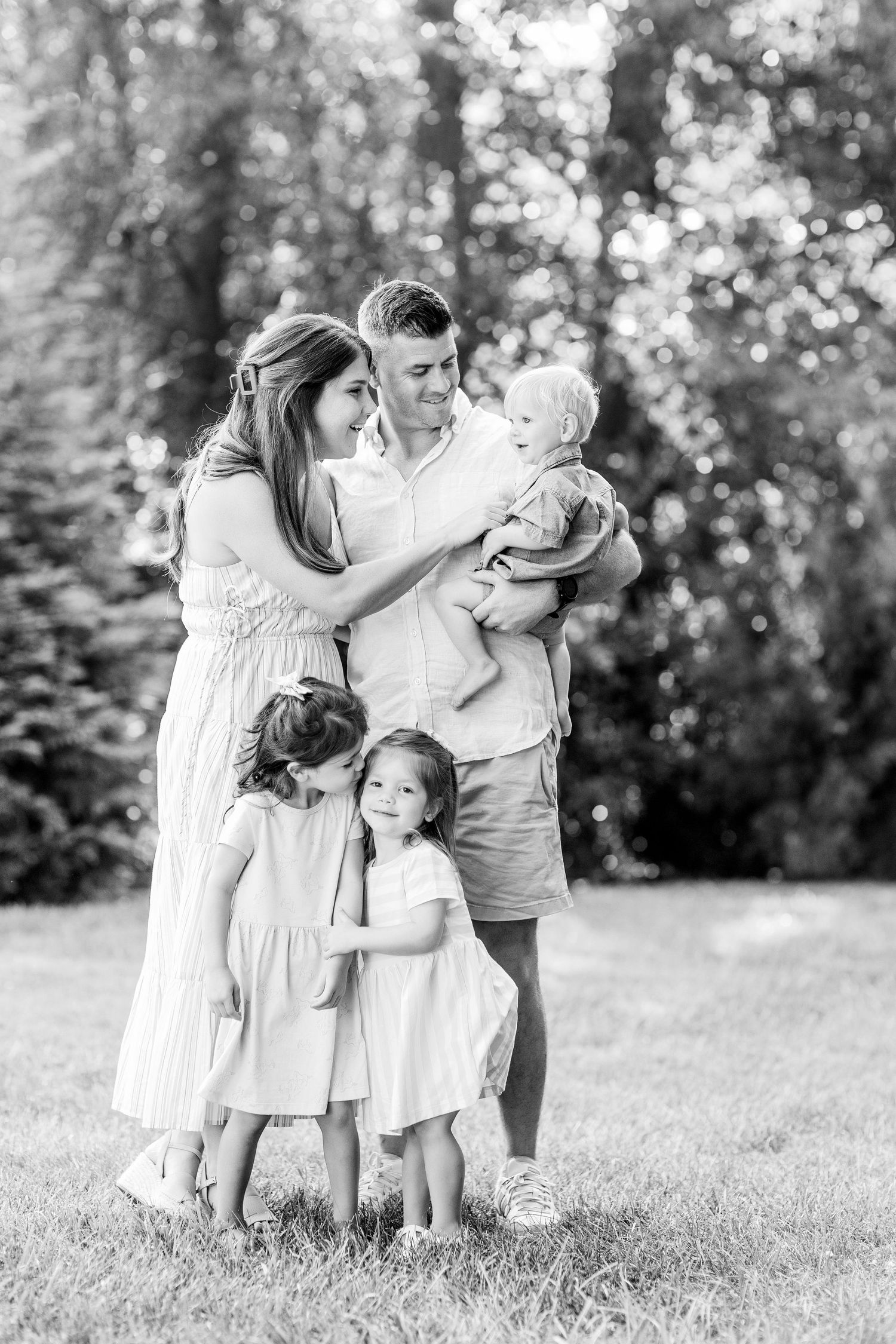 Family in white outfits playing together in black and white outdoor portrait.