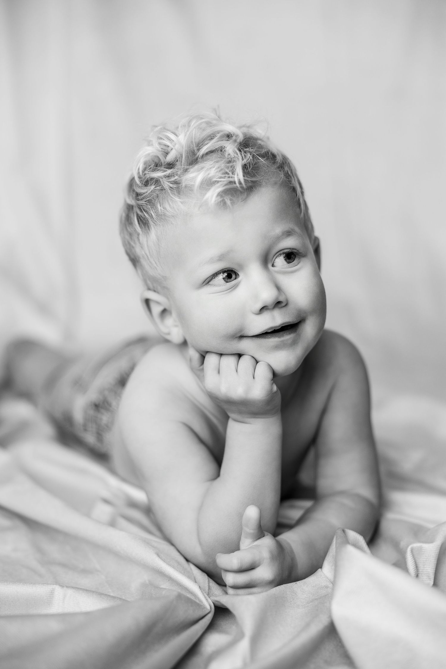 Black and white portrait series of baby on soft white bedding.