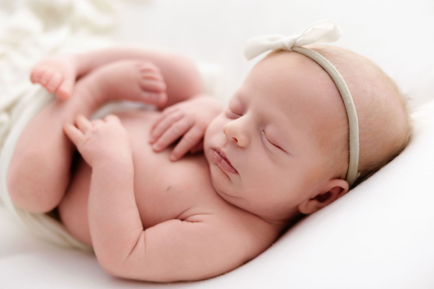 Sleeping newborn baby lying peacefully on white background in soft natural light.