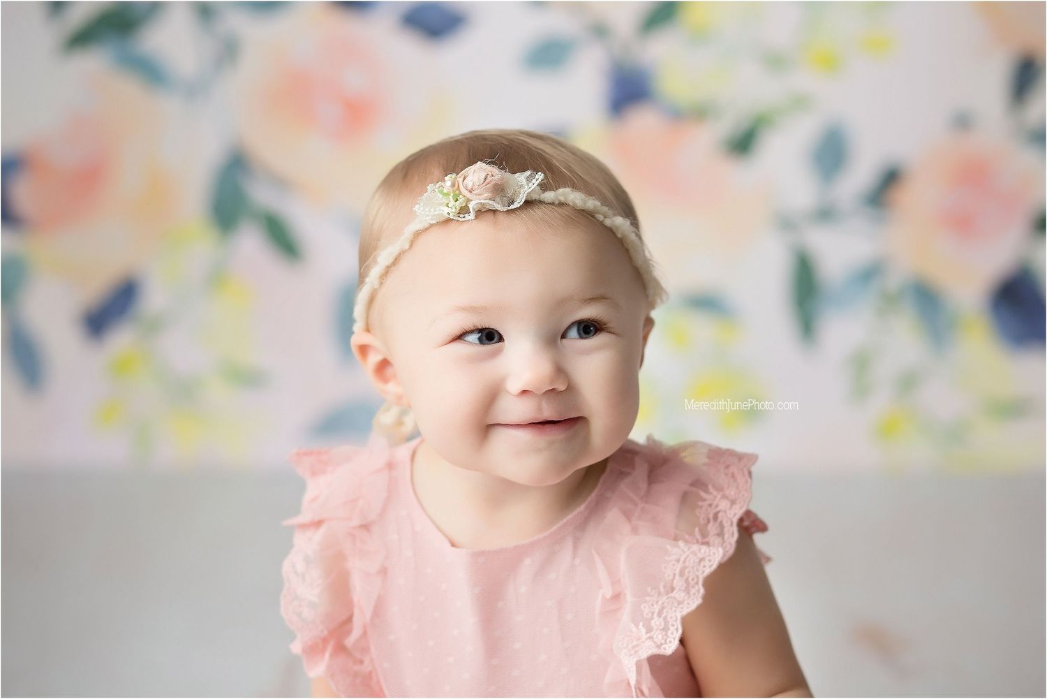 Close-up portrait with floral background and pink ruffled dress.