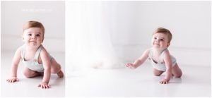 Baby in white tank top crawling and playing on white backdrop during professional photo session.