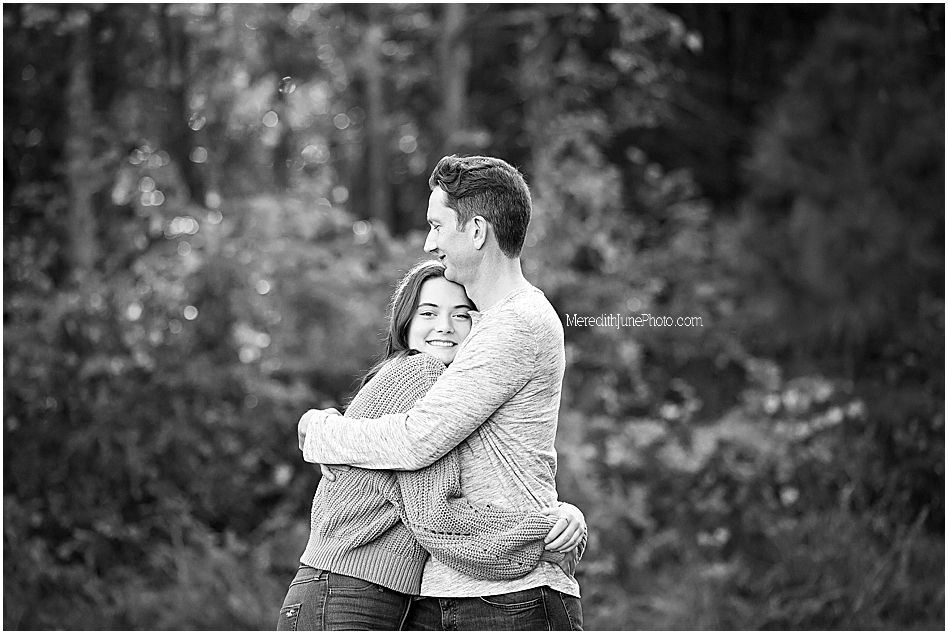 Black and white photograph showing two people embracing outdoors in a candid moment.