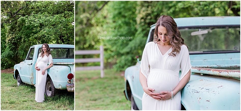A couple in wedding attire poses together near a vintage light blue car during their countryside celebration.