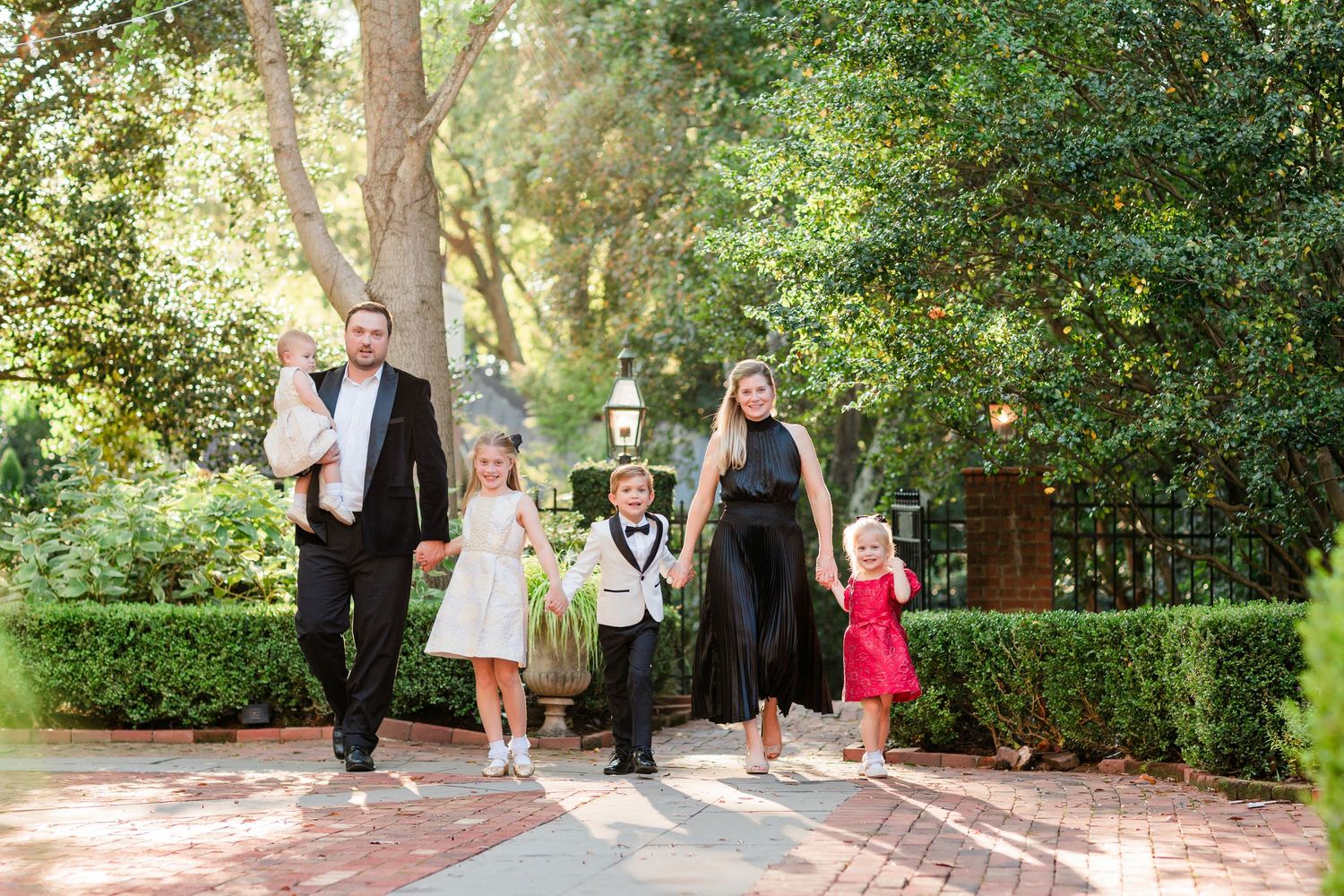 Wedding party members walking along outdoor garden path.