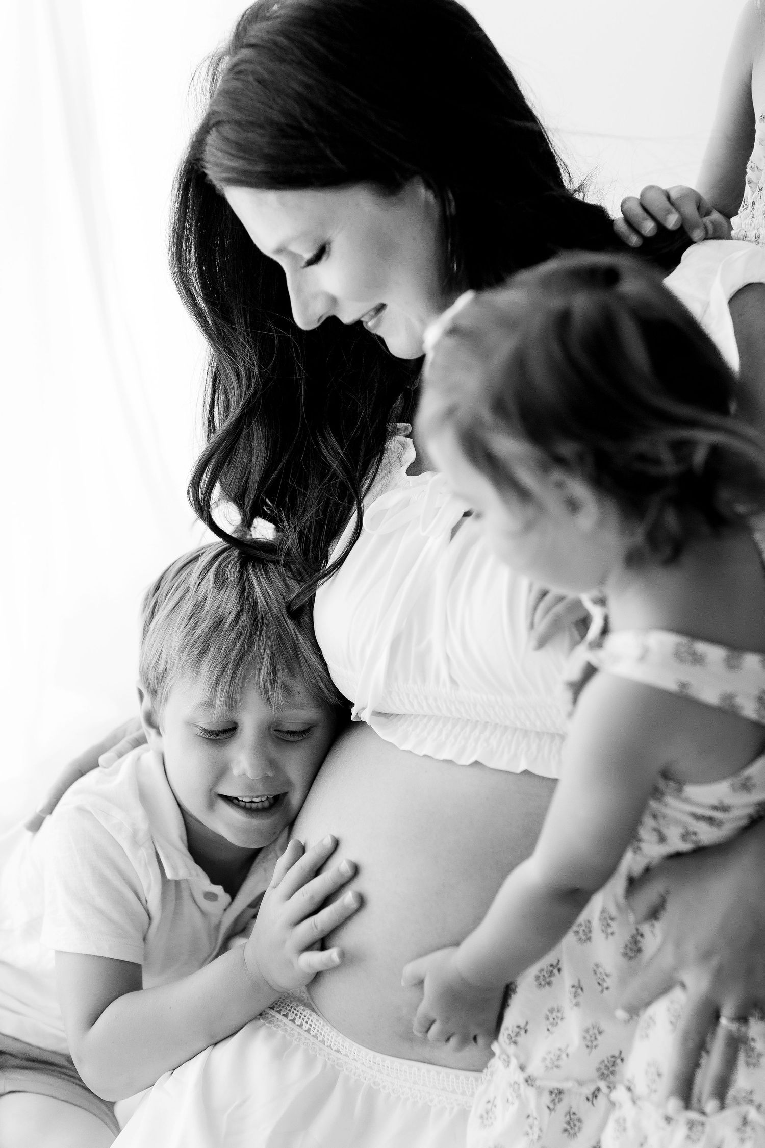 A series of black and white photos showing tender moments between a parent and child during pregnancy.