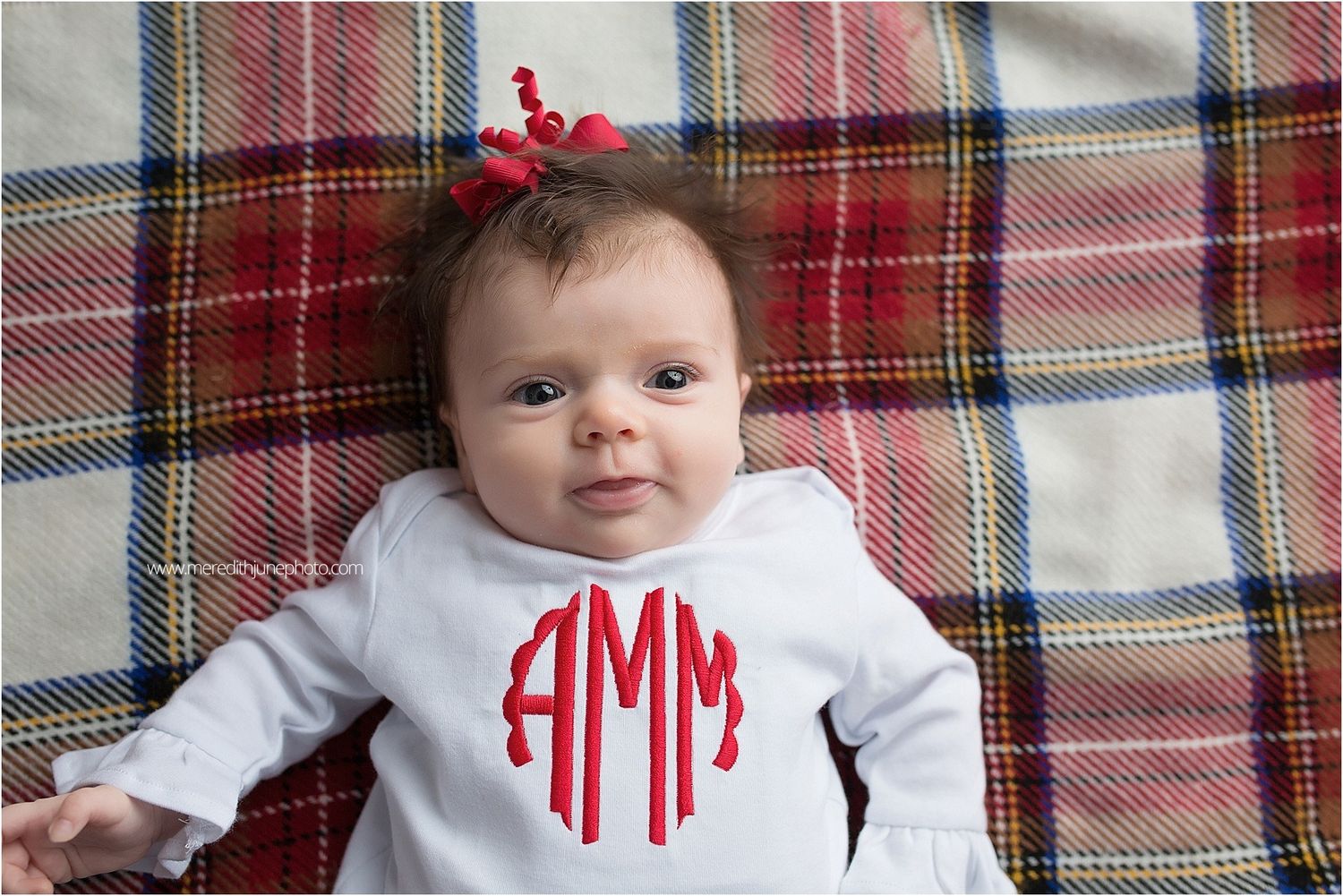 Holiday photo session featuring red and white outfits on plaid blankets with festive decorations.