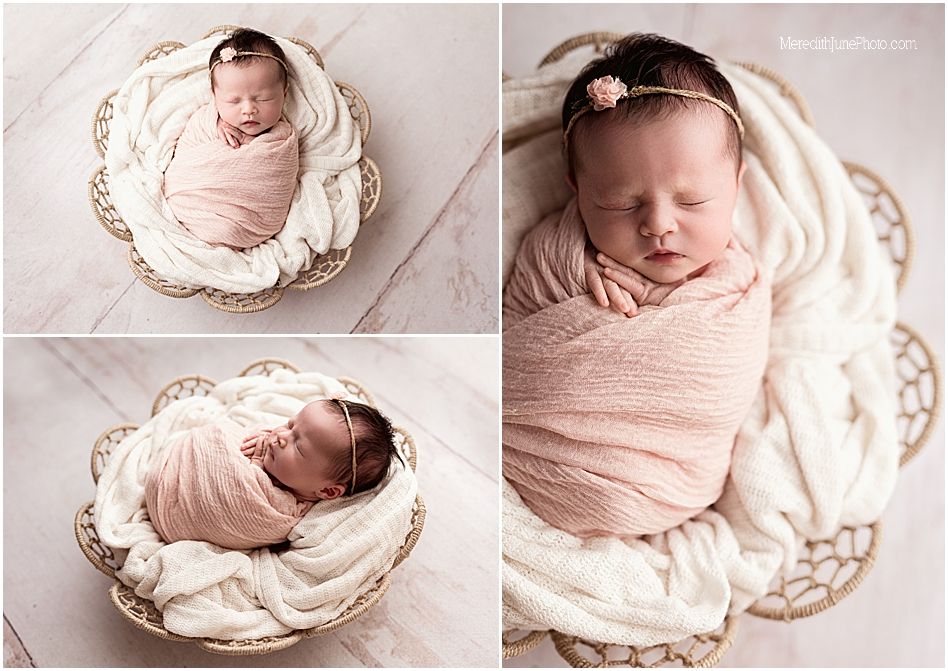 Newborn baby peacefully sleeping in a white lace basket wrapped in soft pink swaddle blanket.