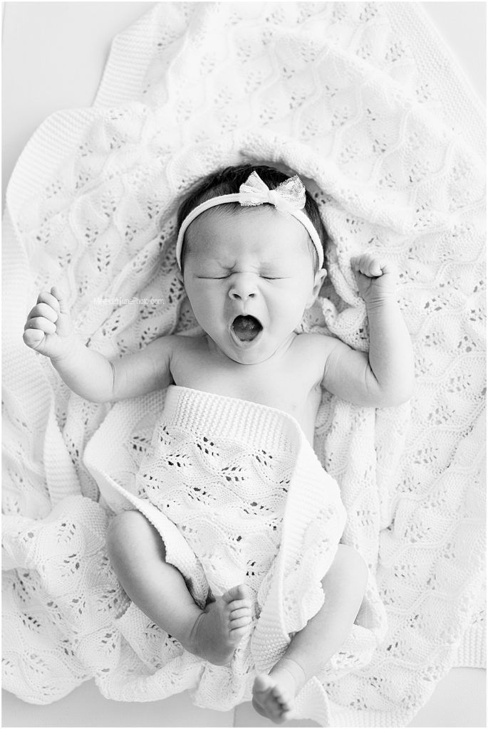 A black and white photo series of a newborn baby lying on white lace fabric showing different expressions.