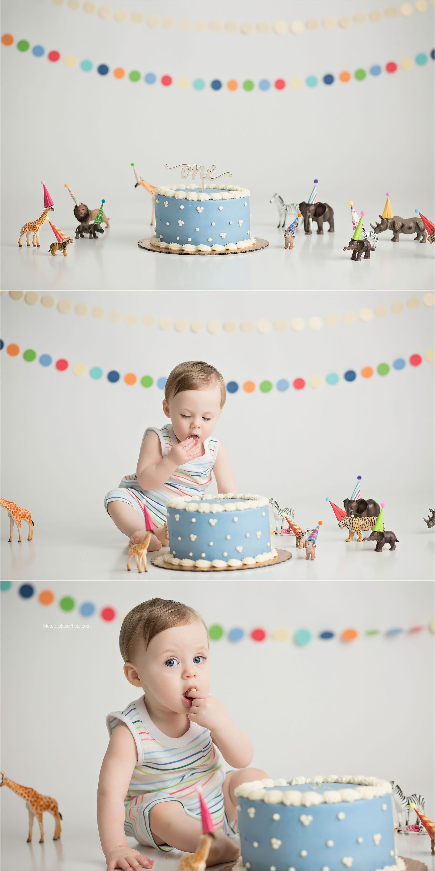 First birthday cake smash photo session with blue polka dot cake and colorful garland decorations against white backdrop.