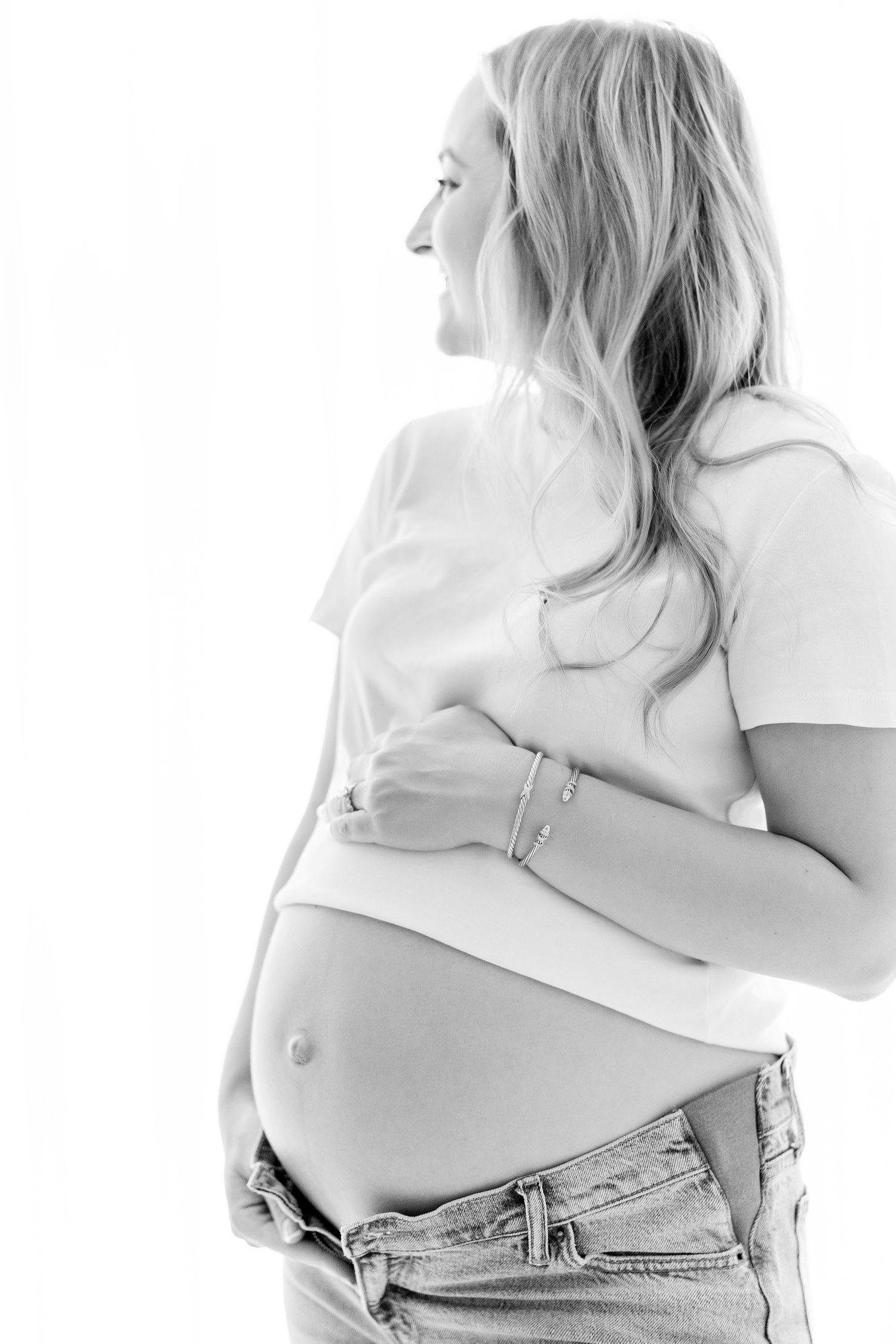 Black and white artistic photo series showing a pregnant belly in denim jeans from different angles.