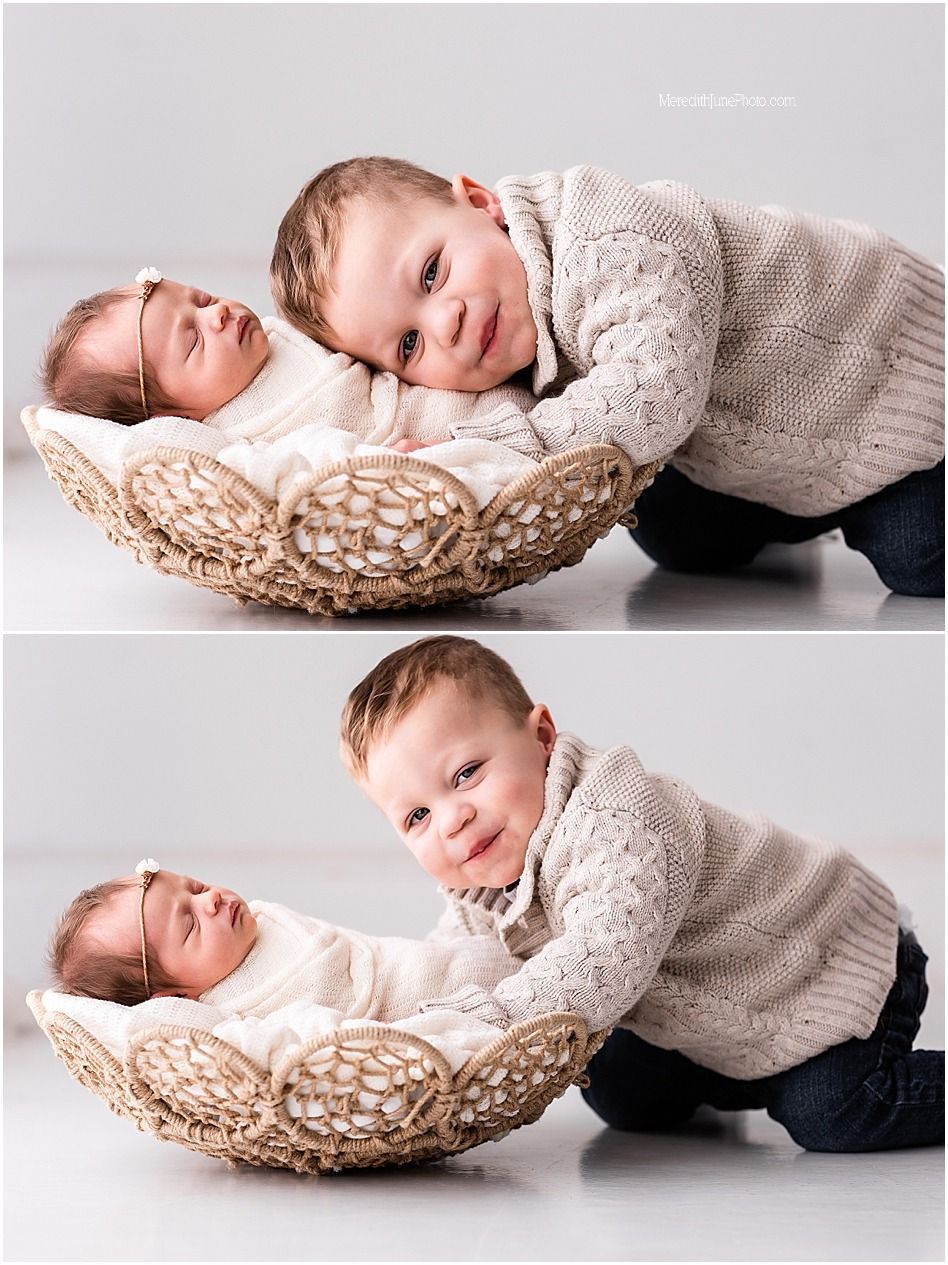 Two siblings share a tender moment as a toddler in a gray sweater leans over a woven basket holding a baby.