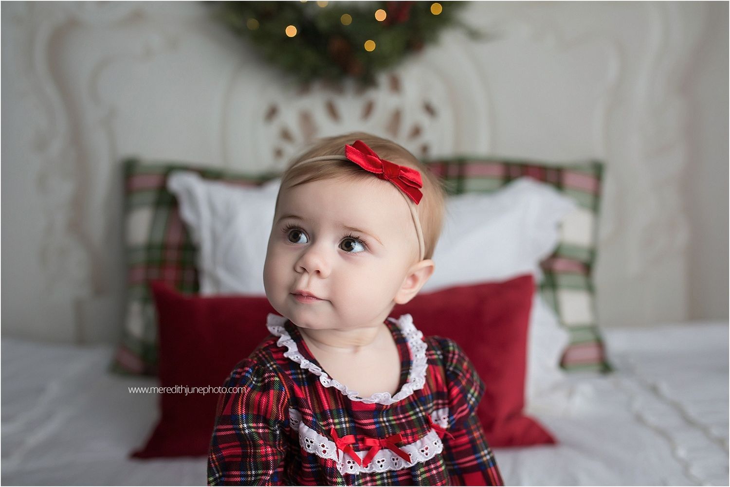 Evergreen Christmas wreath with red berries and plaid decor elements displayed against a light background.