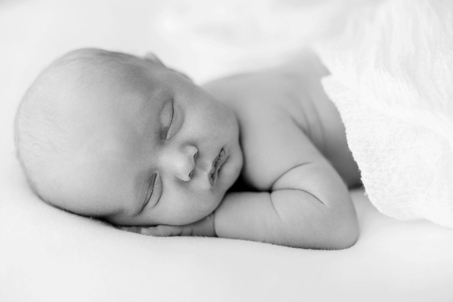 Peaceful newborn baby sleeping soundly, captured in classic black and white photography.