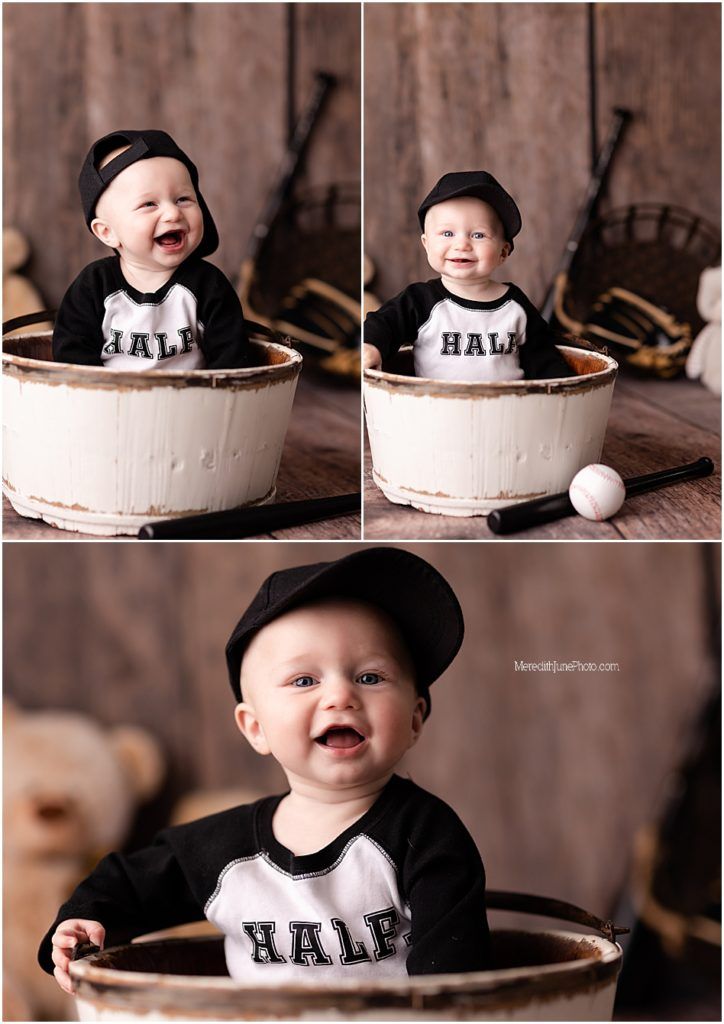A baby wearing a baseball cap sits in a white wooden barrel for a vintage-style photo shoot.