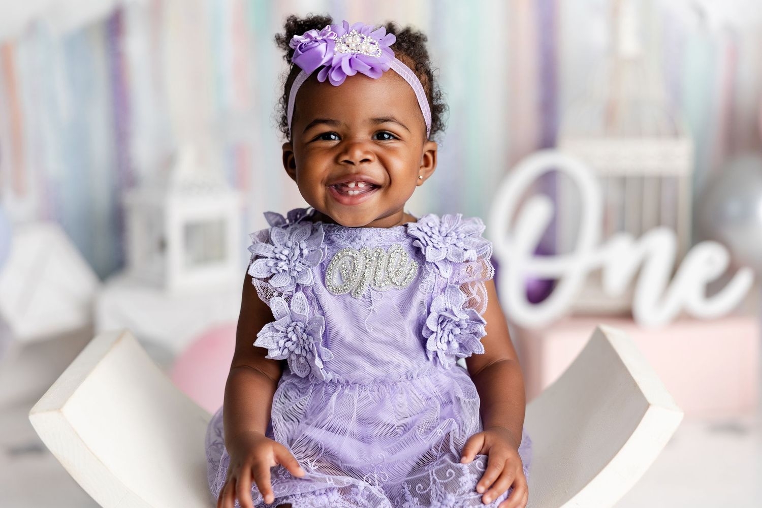 Baby wearing purple dress and headband during milestone photo session.