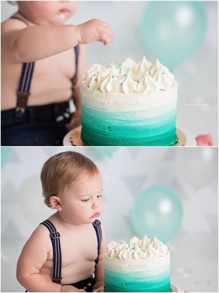 Toddler in dark suspenders explores a beautiful teal ombre cake with white frosting decorations.