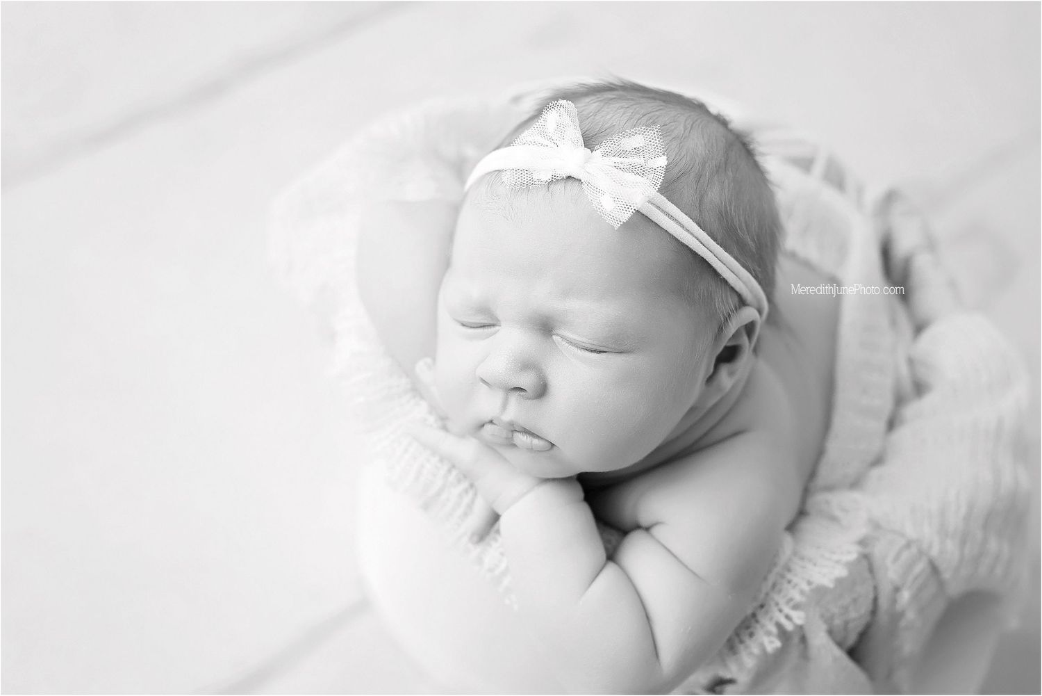 Peaceful newborn baby sleeping on soft white blankets in gentle natural light.