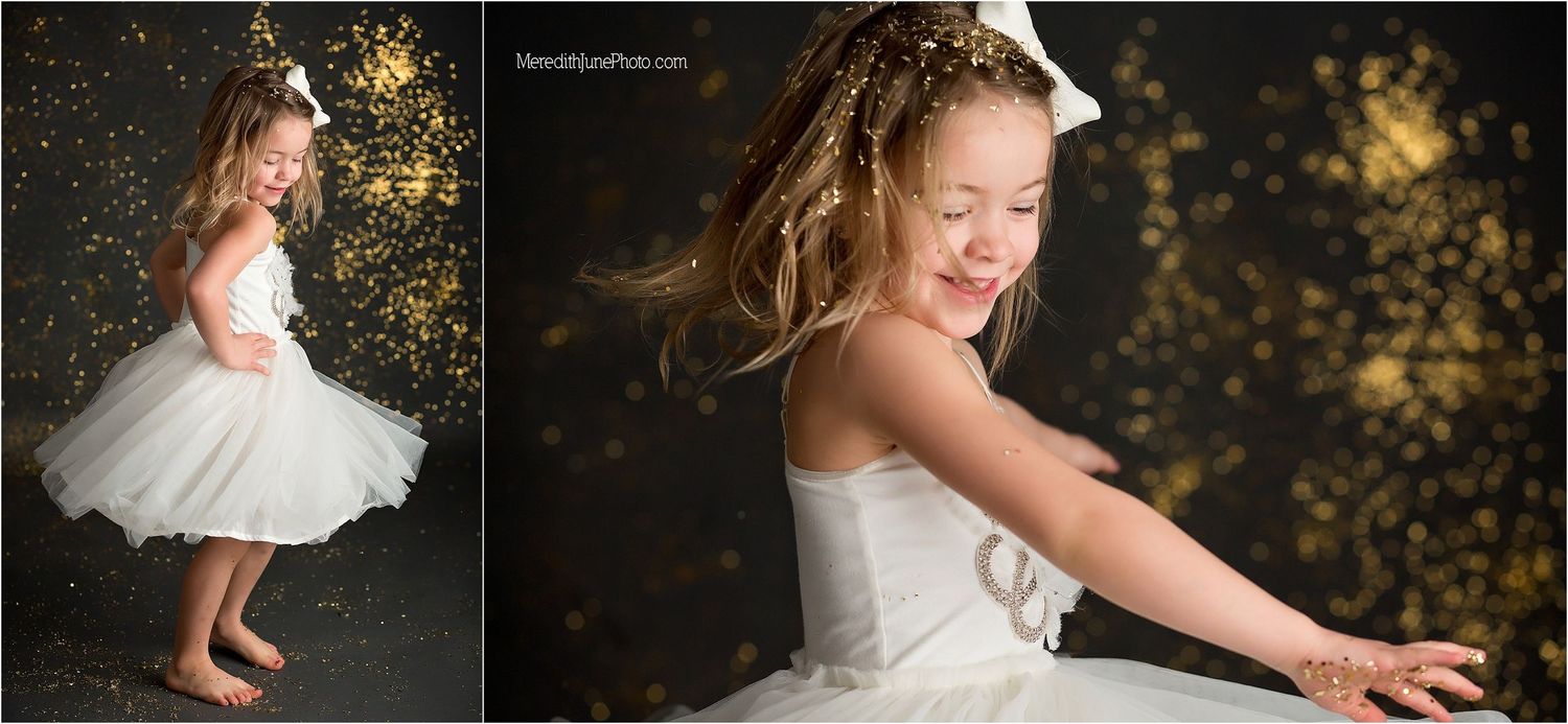 A young dancer in a white tulle dress twirls gracefully against a dark background with glowing bokeh lights.