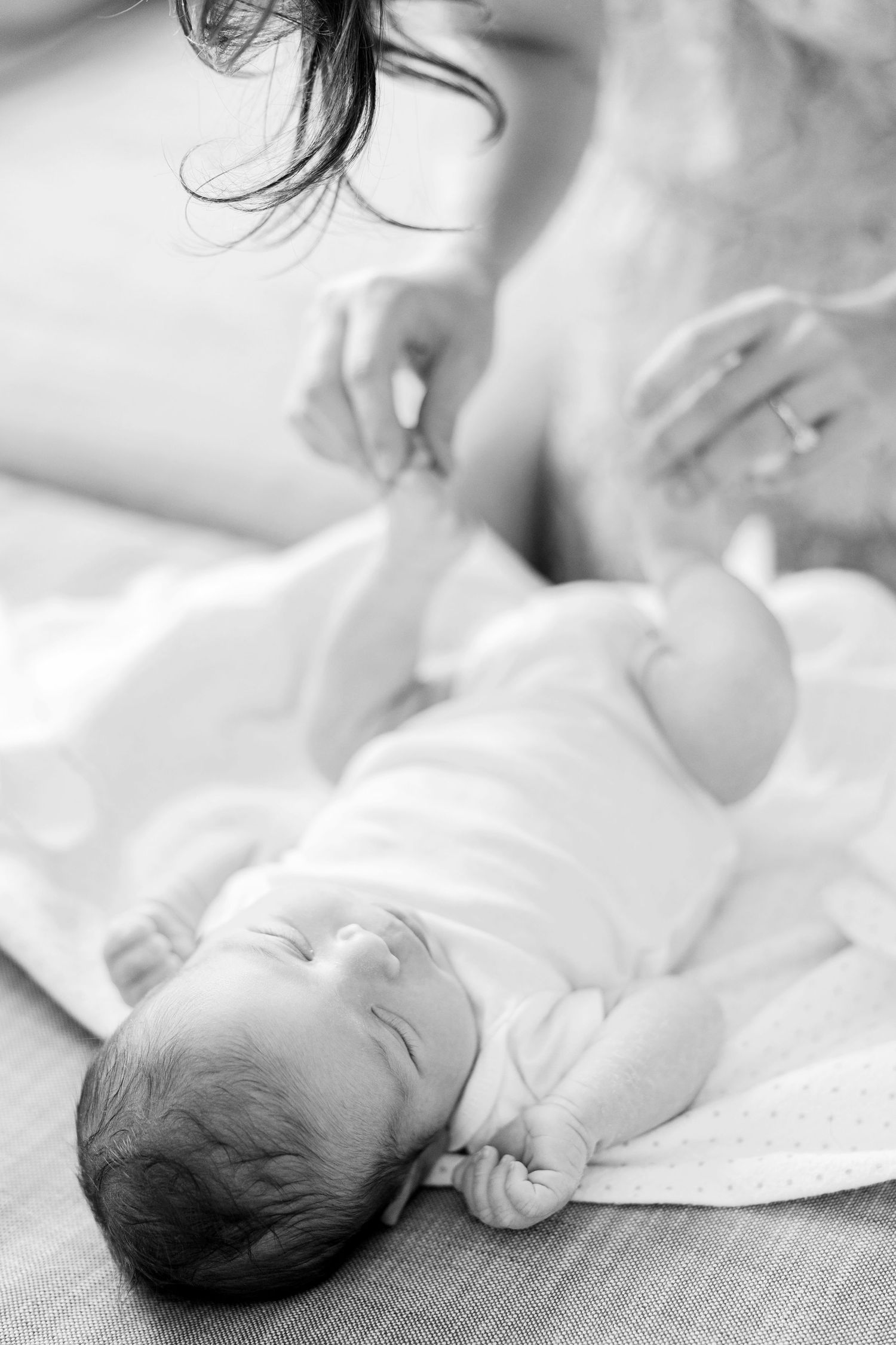 Series of black and white newborn baby photos showing peaceful sleeping poses on white fabric.
