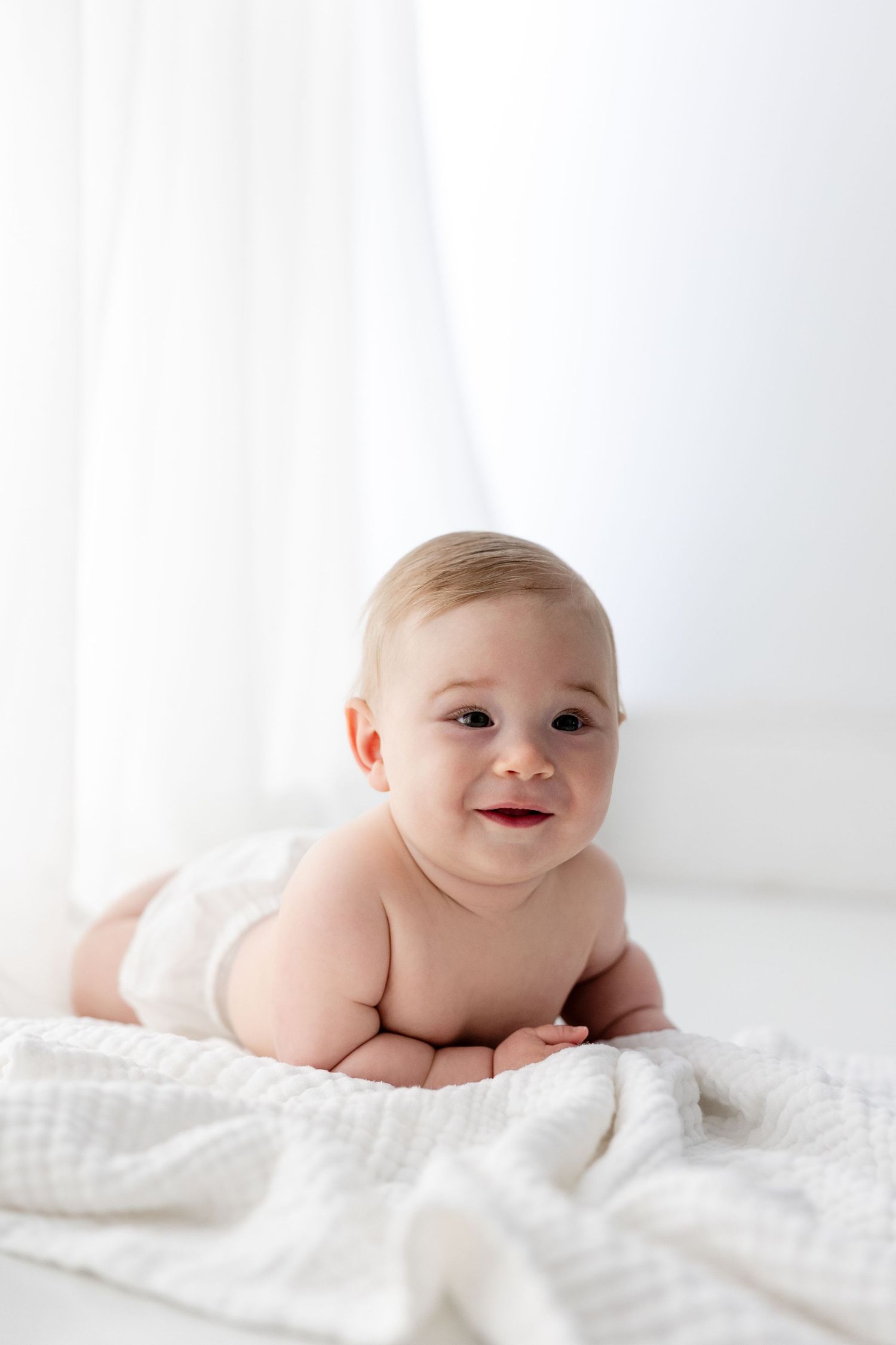 Sweet baby moments captured on white bedding with natural lighting in a minimalist style.