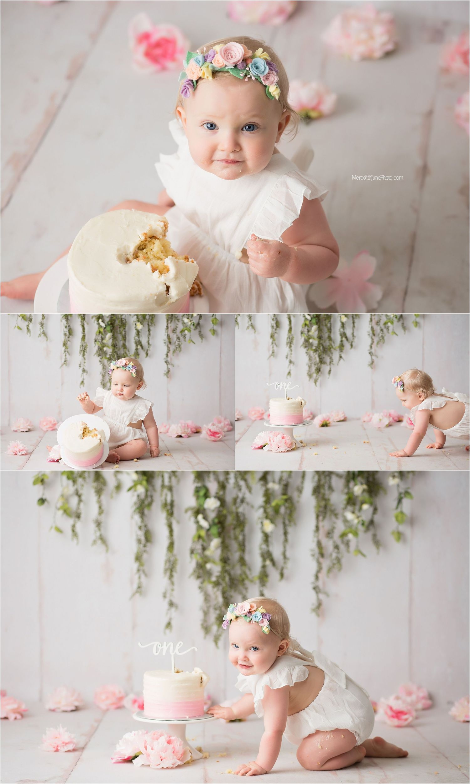 A cake smash photo session with pink and white decor, floral arrangements, and hanging greenery in a studio setting.
