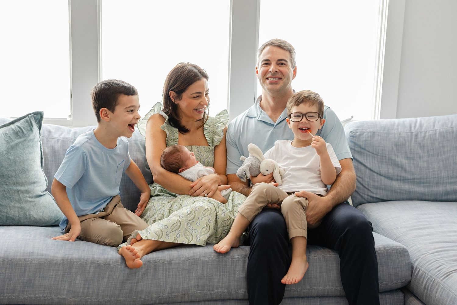 Family relaxing together on a gray couch at home sharing quality time and laughter.