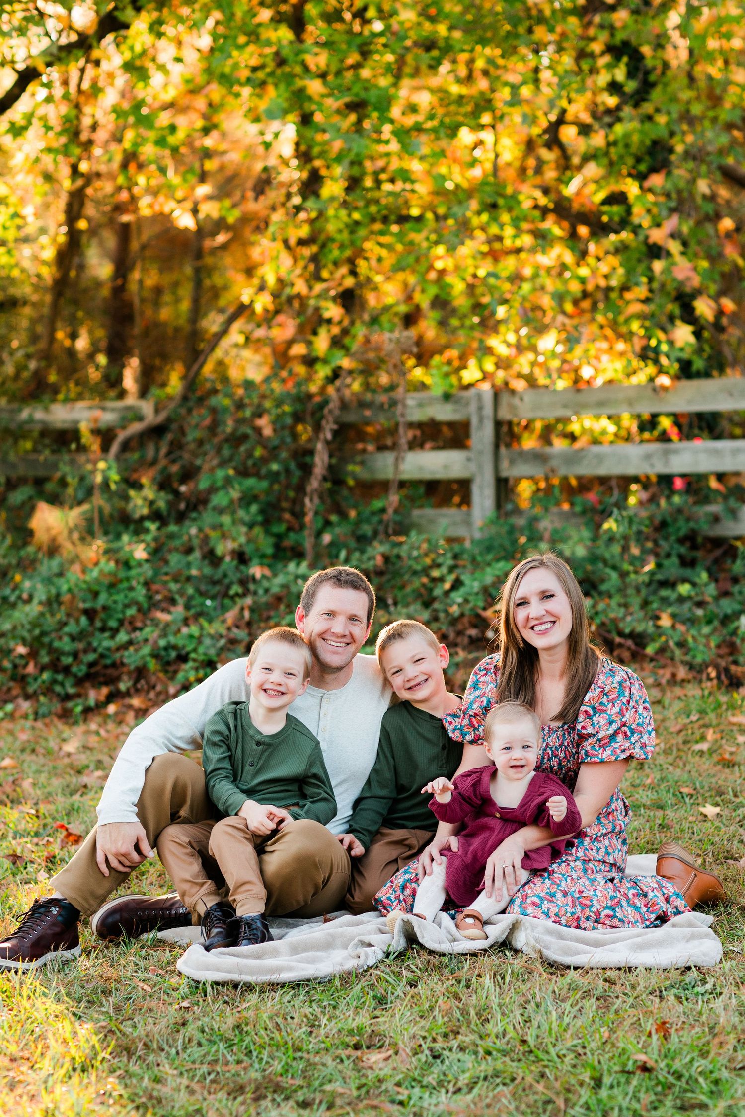 Family relaxing together on blanket outdoors during golden autumn afternoon.