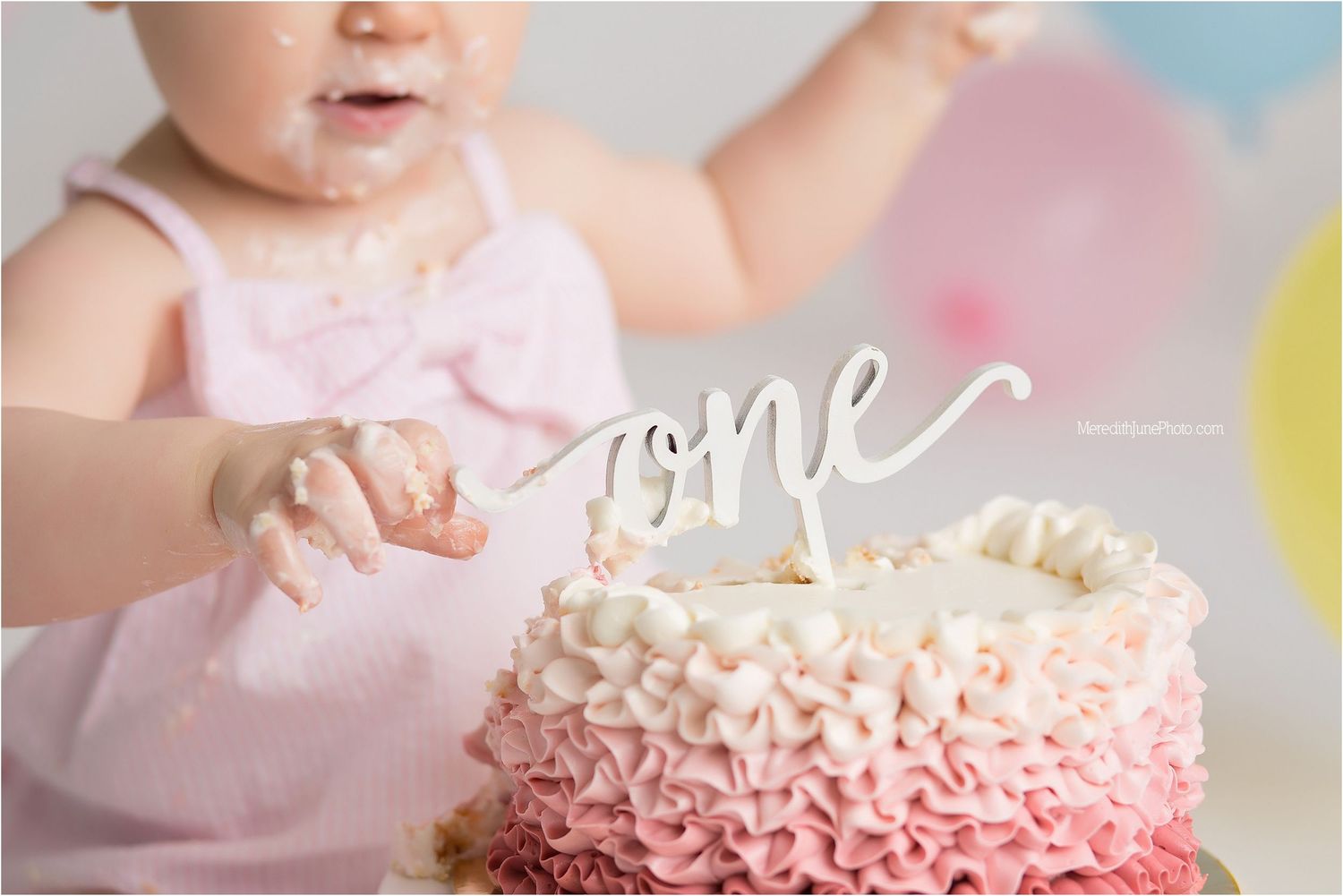 A pink ruffle frosted birthday cake is being smashed and eaten during a festive celebration.
