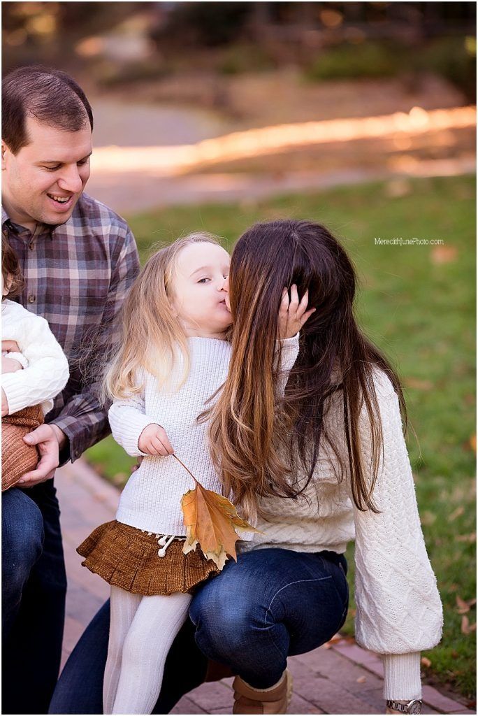 Family enjoying playful moments together during outdoor autumn photo session in the park.