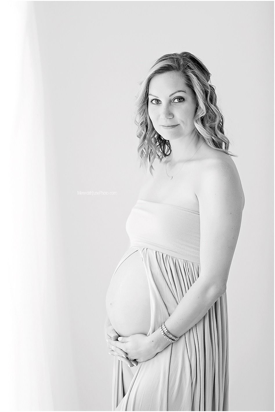 Maternity photo series showing elegant poses in white dress against light background, highlighting pregnancy silhouette.