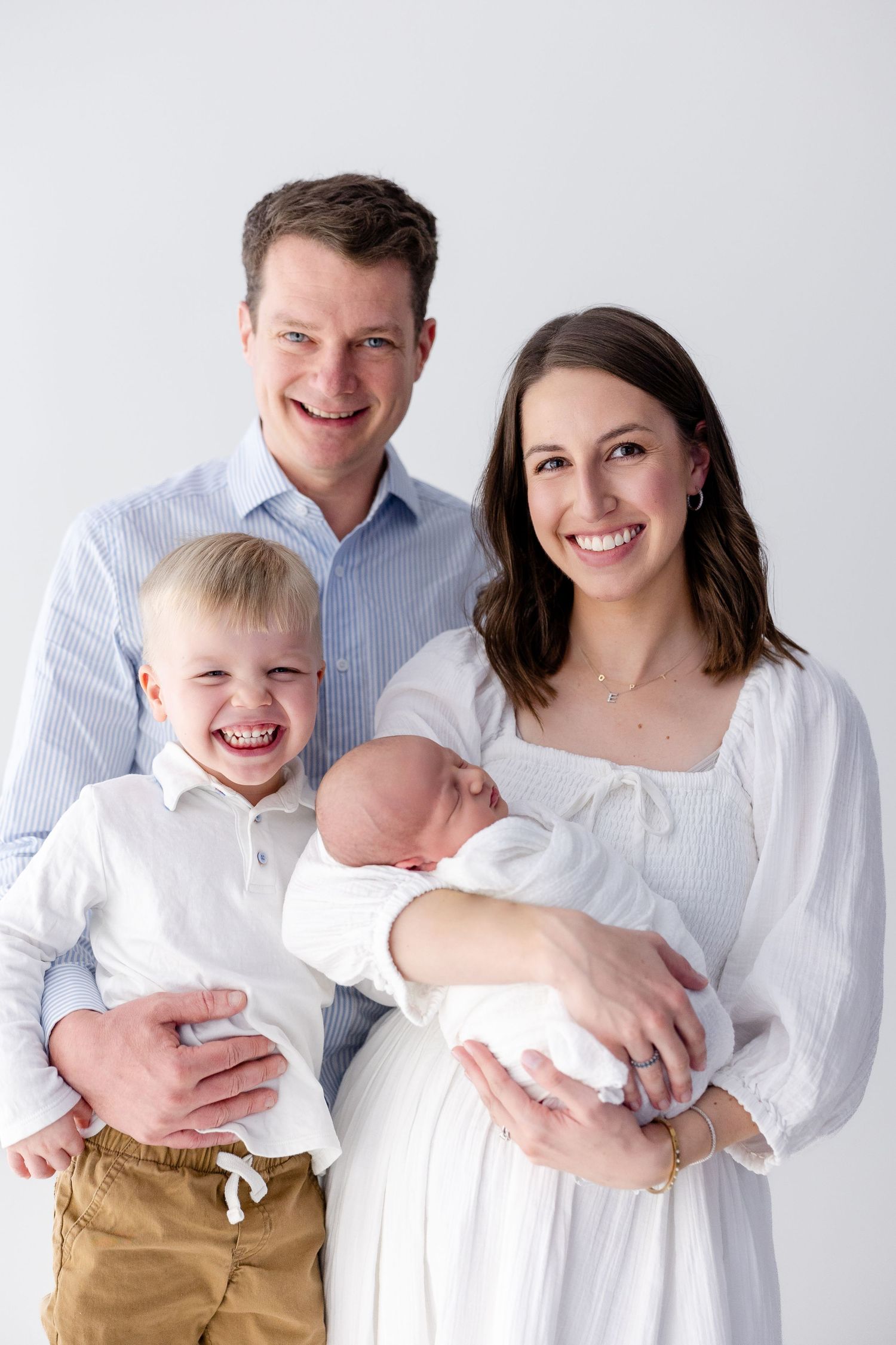 Family portrait in white and khaki clothing against light background.