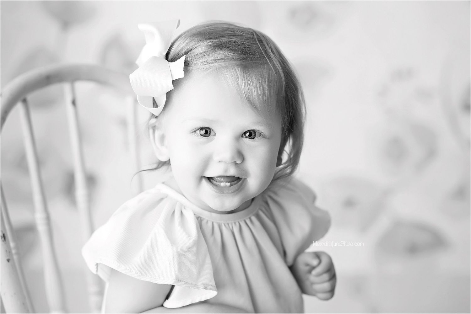 Black and white portrait of baby showing joyful expression during photo session.