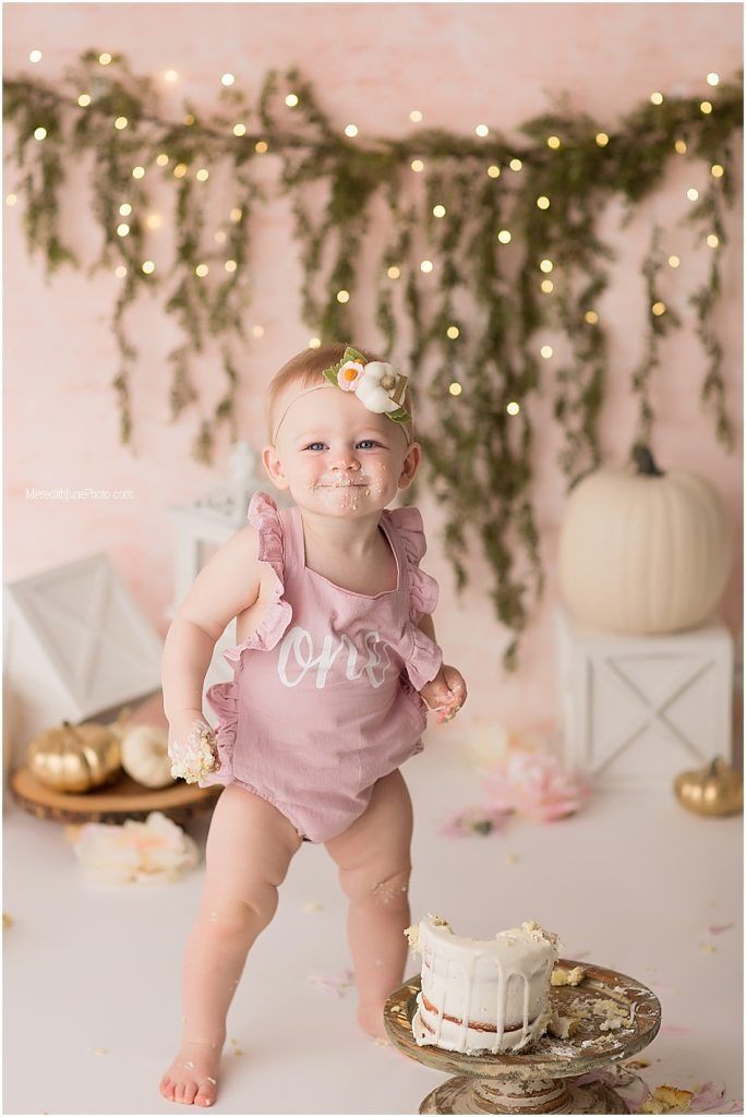 Pink-themed first birthday setup with cake, decorations, and soft lighting.