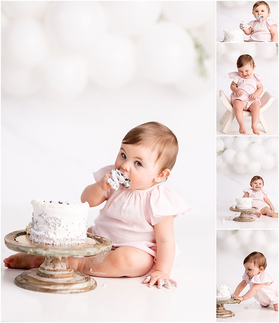 Baby in pink dress explores white cake during first birthday cake smash photoshoot on light backdrop.
