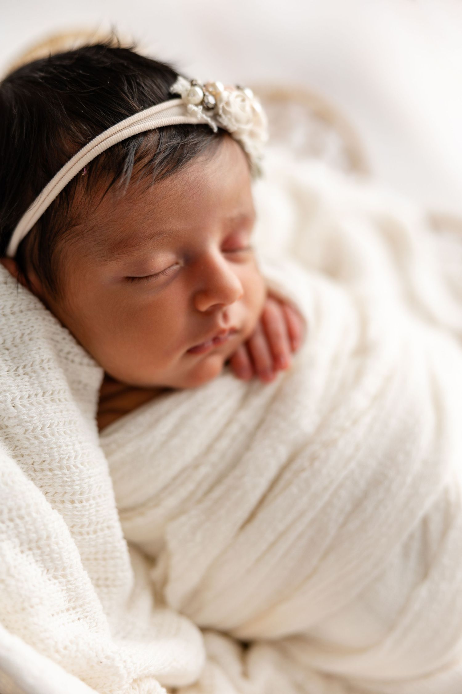 A sleeping newborn baby wrapped in soft white blankets photographed from different angles in a peaceful setting.