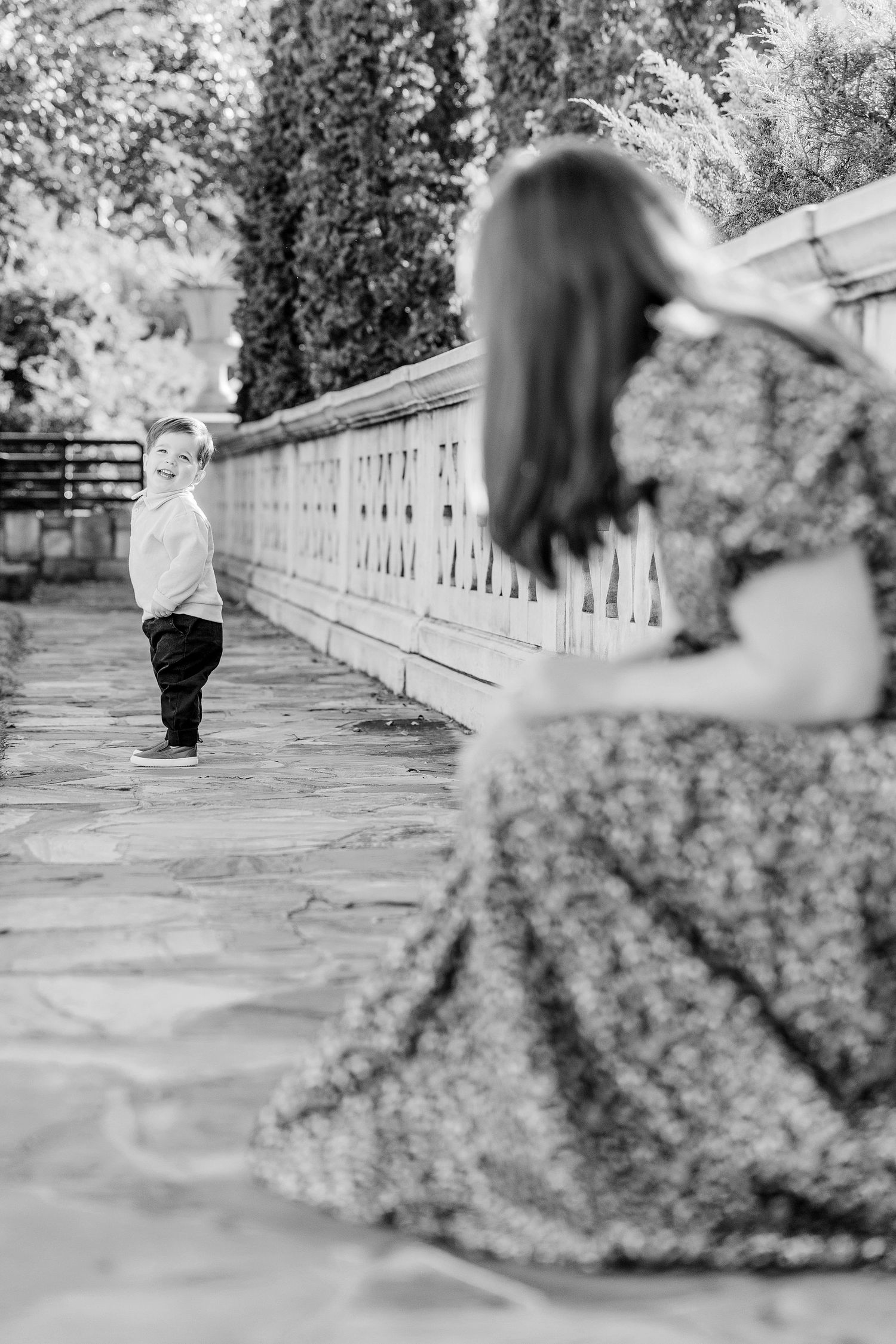 A series of black and white photos showing movement along a stone balustrade walkway in a garden setting.