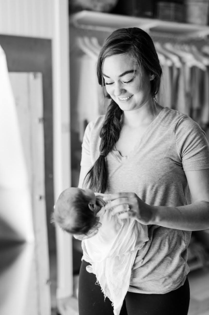 A tender moment captured in black and white as a mother holds and gazes lovingly at her newborn baby.