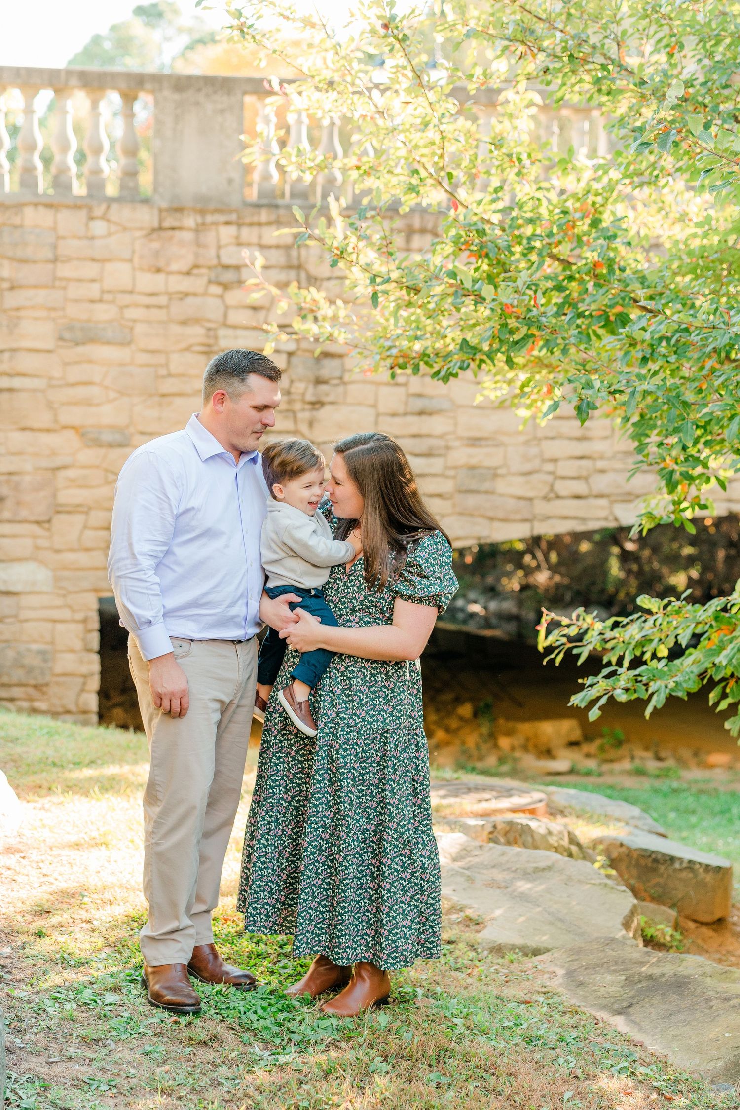 A family shares tender moments together on stone steps surrounded by greenery in matching green outfits.